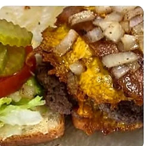 Bacon cheeseburger close-up with melted cheddar and grilled onions