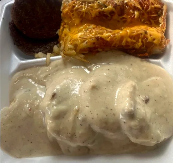 Biscuits and sausage gravy with sausage patties and a cheese-covered hashbrown