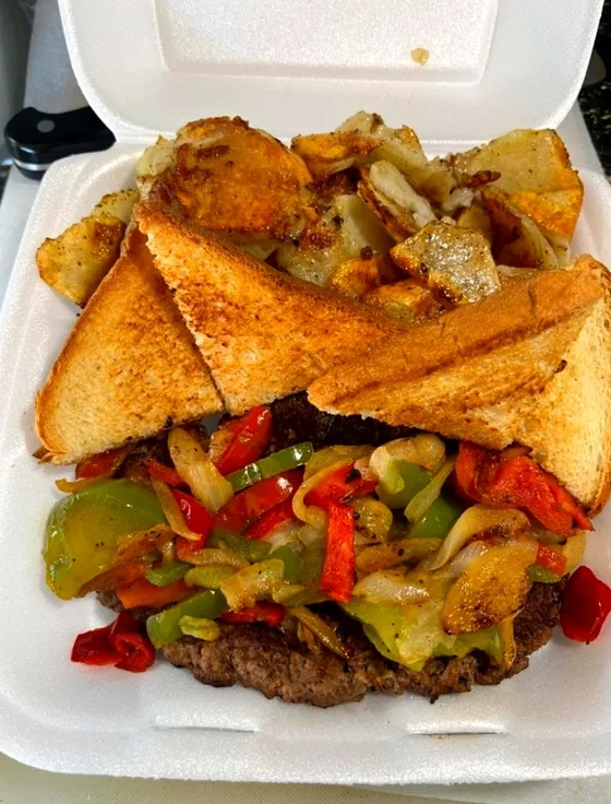 Steak with grilled peppers and onions, Texas toast and fried taters in a takeout box